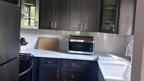 A compact kitchen with dark cabinets, a microwave, a stove, and a sink.