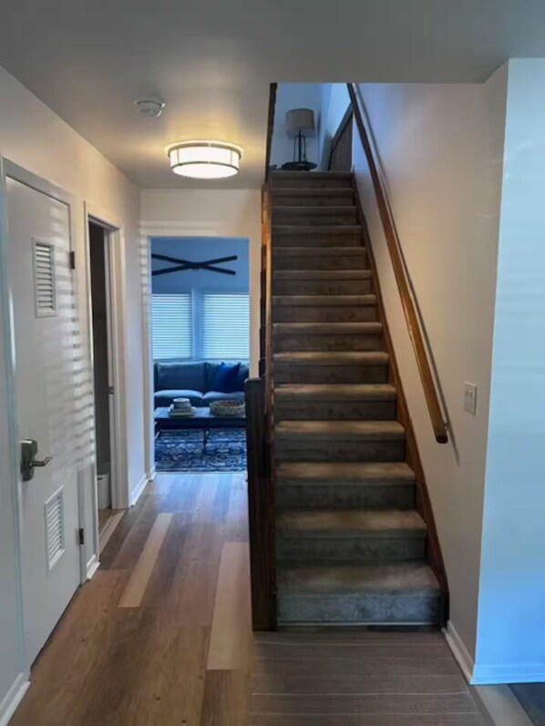 A staircase leading to a living area with a ceiling fan, a sofa, and a lamp.