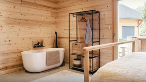 A modern bathroom with a freestanding bathtub, wooden walls, and a large window offering a view of the outdoors. - Chalet Sheehy - Modern property with spa and terraces - OVO Network (La Toussuire)