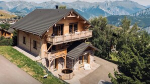 A two-story wooden house with a balcony, a stone fireplace, and a hot tub. - Chalet Sheehy - Modern property with spa and terraces - OVO Network (La Toussuire)