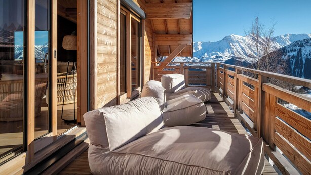 A wooden deck with cushioned seating facing a mountain view. - Chalet Sheehy - Modern property with spa and terraces - OVO Network (La Toussuire)