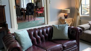 A living room with a dark brown leather sofa, a wooden coffee table, and a large mirror reflecting the dining area. - Trentham Akyra Lodge - 3 bedrooms- Walk to town.  (Trentham)
