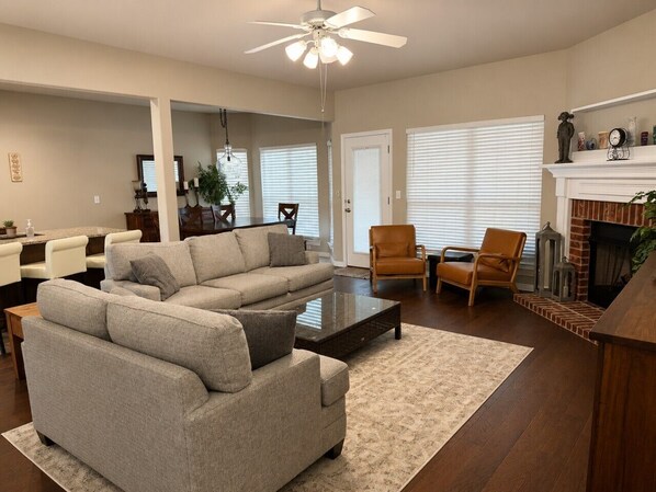 A living room with a sectional sofa, a coffee table, a fireplace, and a ceiling fan.