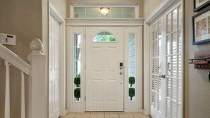Un couloir avec une porte à deux battants, un thermostat et un luminaire placé au-dessus de la porte.
