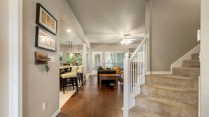 Un vaste espace de vie doté d’un plancher en bois, d’un escalier et d’un coin repas avec des chaises et une table.