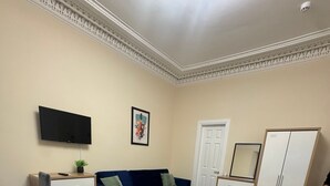 A bedroom with a bed, a TV, a dresser, a wardrobe, and a door.