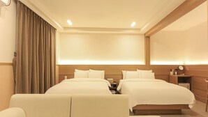 A hotel room with two beds, a sofa, a desk, and a mirror. - Staylibera (Gangneung)