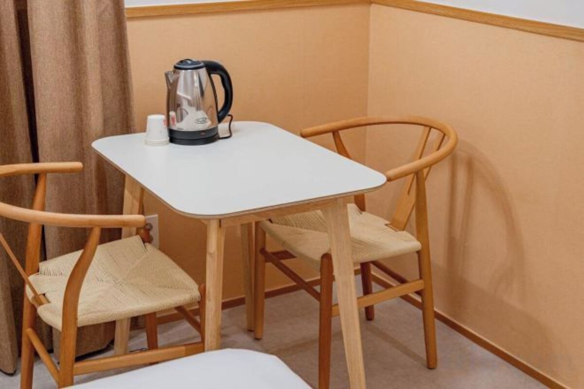 A small room with a white table and two wicker chairs.