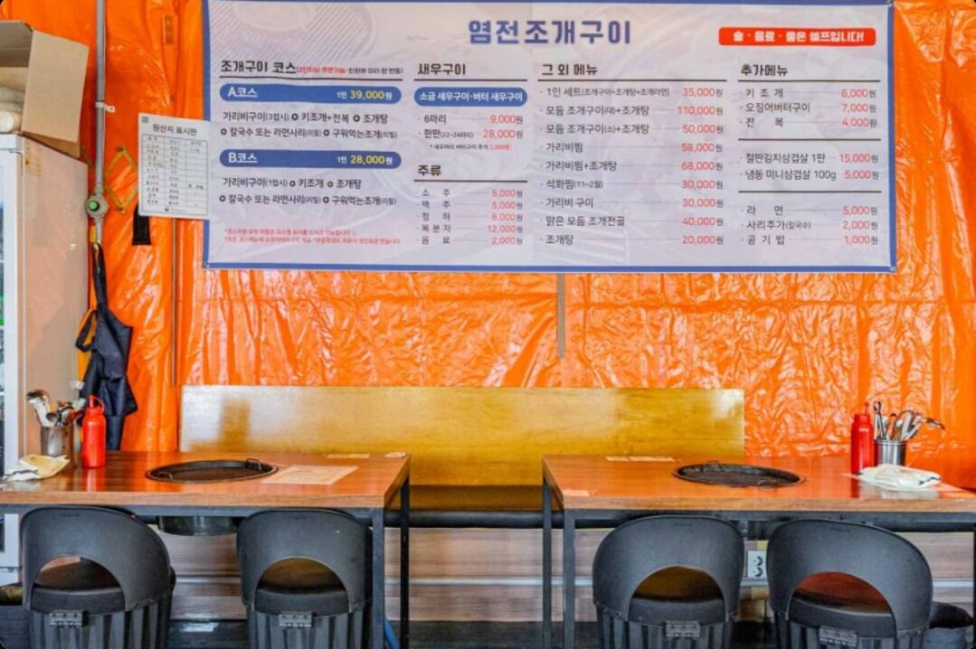 L’intérieur d’un restaurant, avec un tableau affichant le menu, des tables et des chaises.