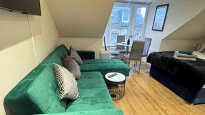 A modern living room with a green sectional sofa, a round coffee table, and a black sofa. - Room-apartment 5- 216 High Street (Arbroath)