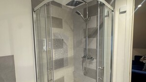 A modern bathroom with a glass-enclosed shower, a white sink, and a tiled floor. - Apartment 6- 216 High Street (Arbroath)