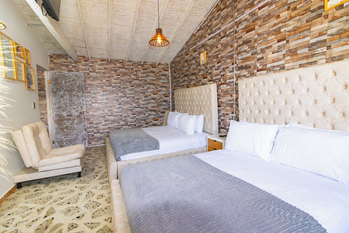 Een kamer met twee bedden, een stoel en een muur met baksteenmotief.