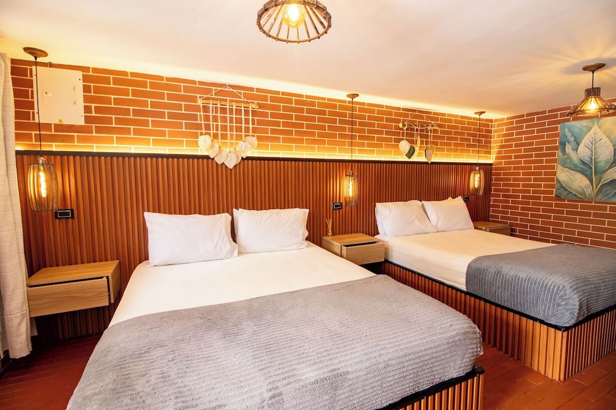 Een hotelkamer met twee bedden, houten lambrisering, bakstenen muren en wandlampen.