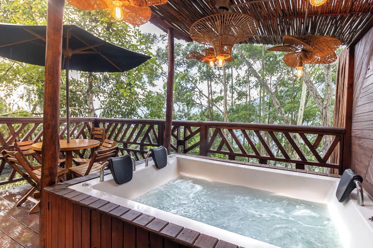 Een houten terras met een jacuzzi, houten stoelen en een tafel.