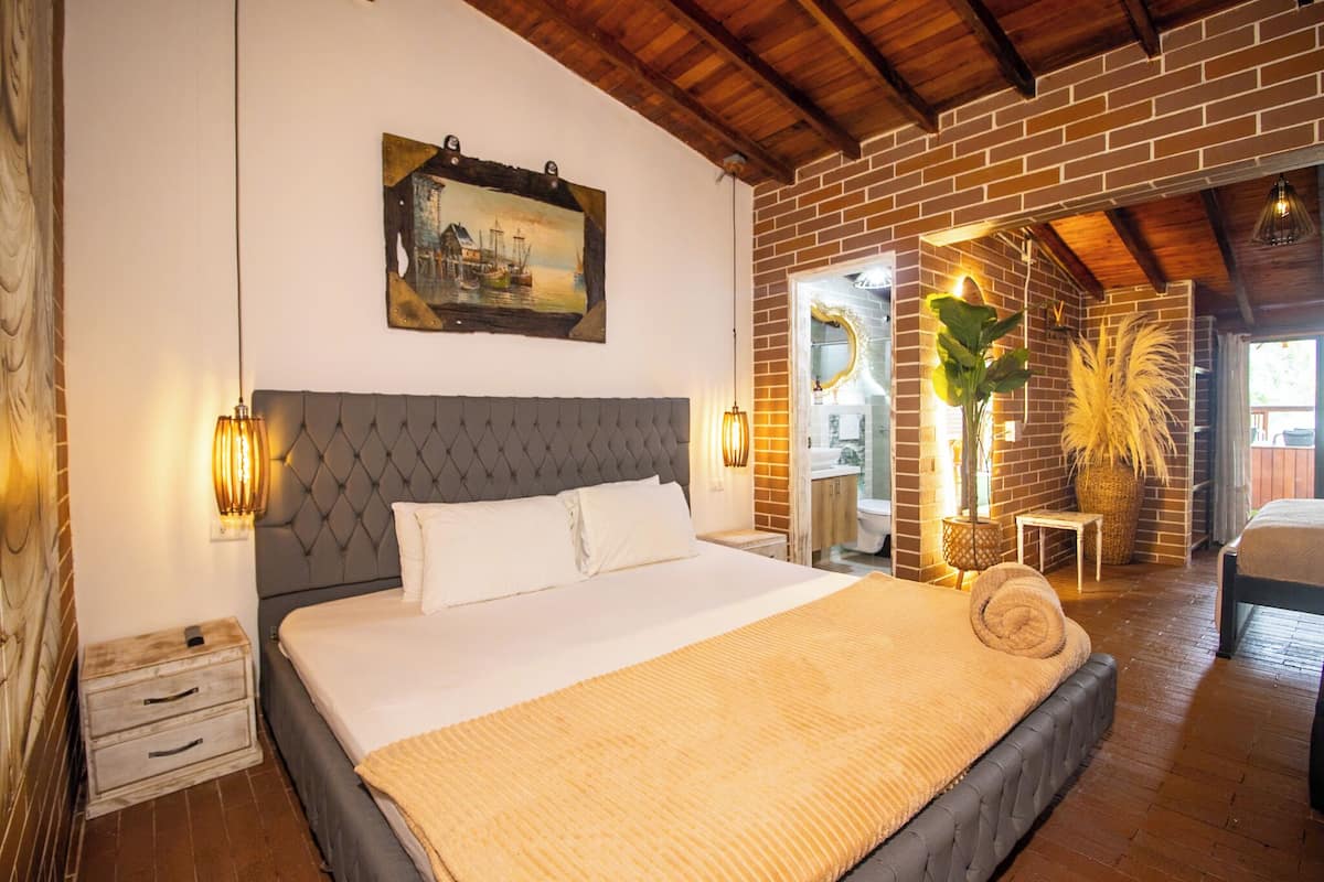 Een ruime slaapkamer met een groot bed, een houten hoofdbord en een bakstenen muur.