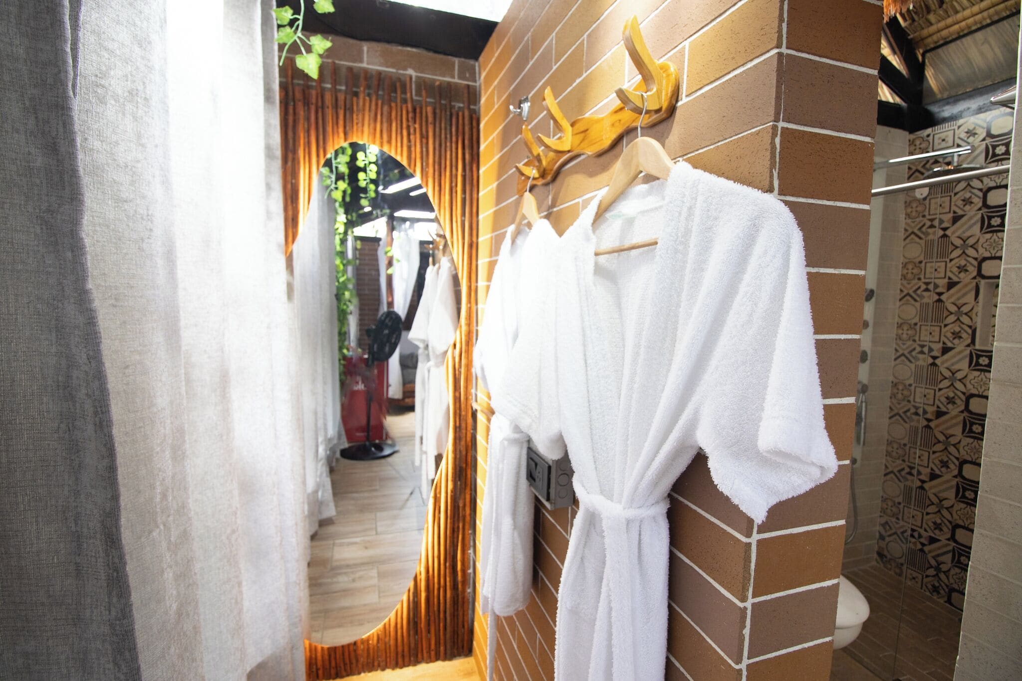 A bathroom with a brick wall, a hanging robe, and a patterned tile backsplash.