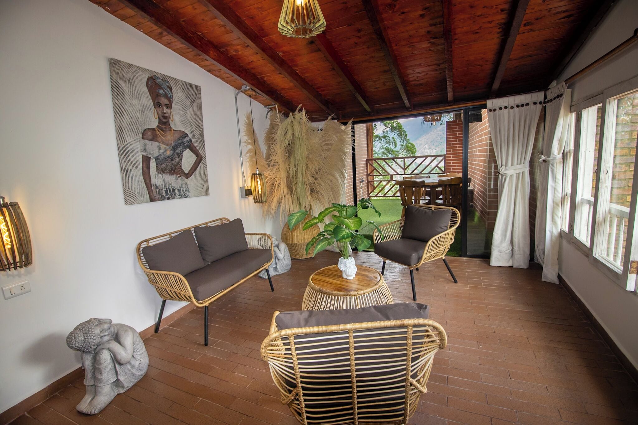 A cozy room with wicker furniture, a painting on the wall, and a view of the outdoors.