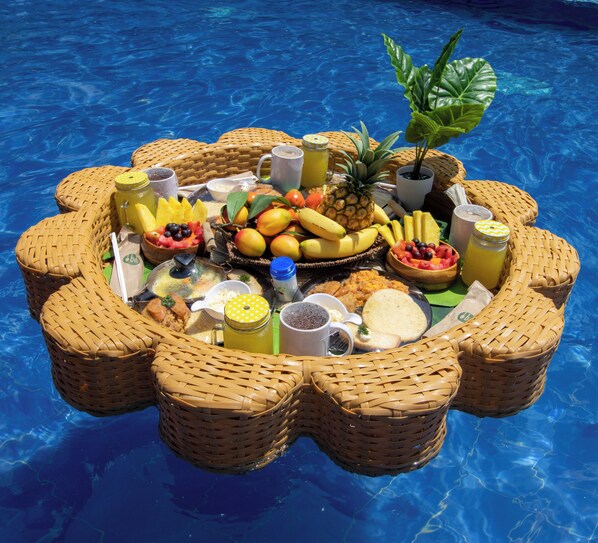A floating dining setup with various fruits, beverages, and snacks in a pool. - Hotel Glamping La Polka (Amaga)
