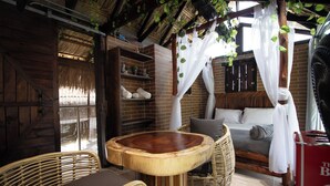 Een rustieke houten kamer met een bed, rieten meubels en een grote houten tafel.