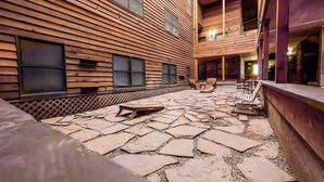 Ein Holzhaus mit einer Steinterrasse, Sitzmöglichkeiten im Freien und einem Poolbereich.