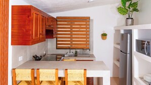 Une cuisine avec des meubles en bois, un plan de travail blanc et un réfrigérateur en acier inoxydable.