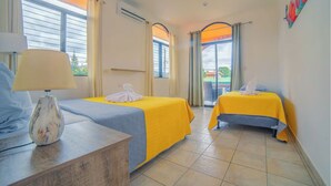 A hotel room with two beds, a lamp, and a view of the outside. - Oasis 17 - Group Getaway (La Fortuna)