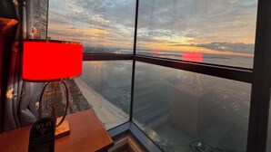 A room with a large window offering a view of a cityscape and a body of water during sunset. - KanStay Sea View Condo by Manila Bay｜康宿·海境居 (Manila)