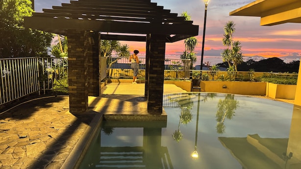 A pool area with a pergola, a lamp post, and a view of palm trees and a sunset. - KanStay Sea View Condo by Manila Bay｜康宿·海境居 (Manila)