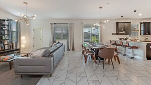 Ein modernes Wohnzimmer mit einer Couch, einem Essbereich mit Stühlen und einer Küche mit Barhocker.