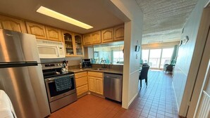 A kitchen with wooden cabinets, stainless steel appliances, and a tiled floor. - Relaxing Beachfront Oceanview Condo w/2 Beds 2 Full Baths, Kitchen, Pet Friendly (Galveston)