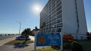 A tall white building with a sign reading "By The Sea Condominiums". - Relaxing Beachfront Oceanview Condo w/2 Beds 2 Full Baths, Kitchen, Pet Friendly (Galveston)