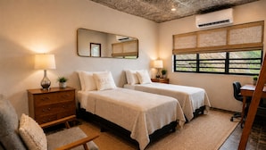 Een slaapkamer met twee bedden, een bureau, een stoel, een dressoir, een spiegel en een raam met uitzicht.