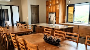 Een ruime keuken met houten kastjes, een groot eiland en een eethoek met houten stoelen.