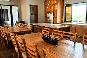 A spacious kitchen with wooden cabinets, a large island, and a dining area with wooden chairs.
