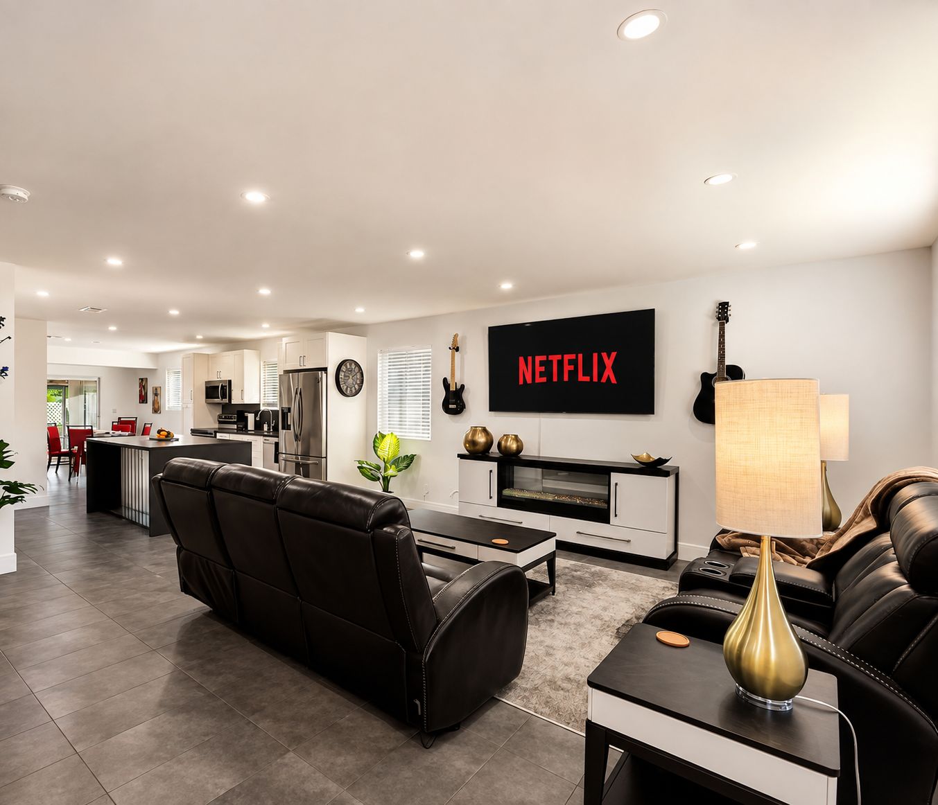 A modern living room with a black leather sofa, a coffee table, and a TV mounted on the wall displaying 'NETFLIX'.