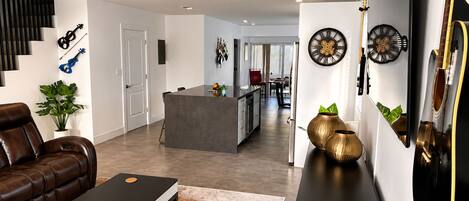 A modern living room with a leather sofa, a coffee table, and a kitchen area in the background.