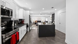Una cocina moderna con electrodomésticos de acero inoxidable, una isla central y un comedor con encimera oscura.