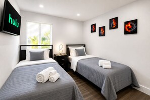 Une chambre d’hôtel avec deux lits, une télévision, des œuvres d’art au mur et une fenêtre avec des stores.