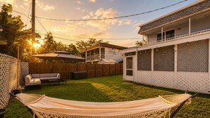 A backyard with a hammock, a covered seating area, and a house with a balcony. - 3BR Guitar House + Poker Lounge Near Hard Rock (Hollywood)
