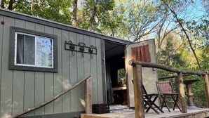 A cabin with a wooden deck, a window, and a door leading to an interior space.