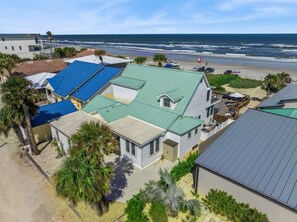 Une propriété située en bord de mer, comprenant plusieurs maisons, offrant une vue sur la plage et un ciel dégagé.