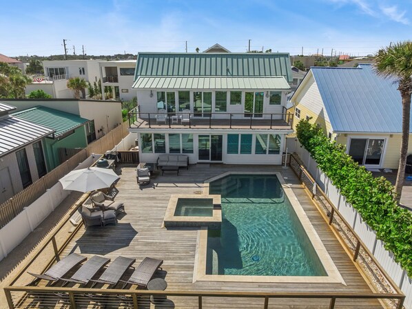 Une maison à deux étages dotée d’une grande terrasse, d’une piscine et d’un patio couvert.