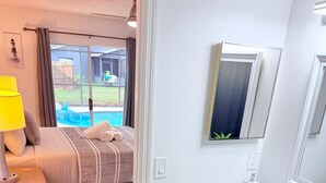 Ein Schlafzimmer mit Bett, Nachttisch und Blick auf einen Pool.