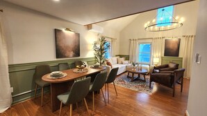 A dining area with a wooden table and chairs, a sofa, and a chandelier.