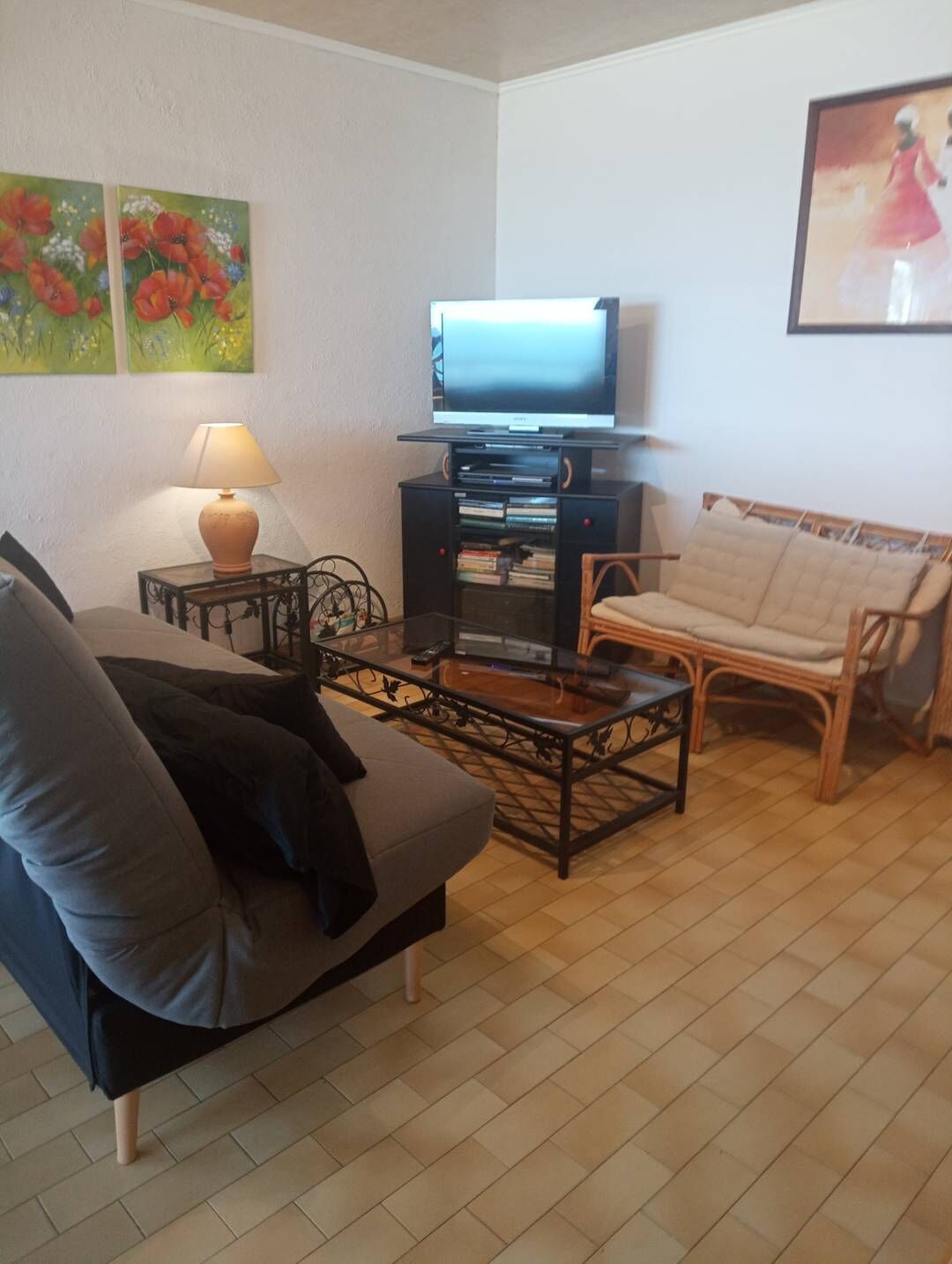 A living room with a sofa, a coffee table, a TV on a stand, a lamp, and a chair.