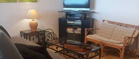 A living room with a sofa, a coffee table, a TV on a stand, a lamp, and a chair.