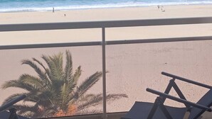 Una mesa con dos vasos y un bol, con vista a una playa con palmeras y una vista despejada del océano.