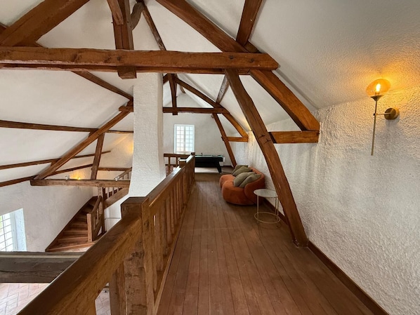 A loft-style room with exposed wooden beams, a wooden staircase, and a cozy seating area with cushions. - Domaine du Patineau (Chevillon-sur-Huillard)