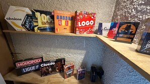 Une étagère contenant divers jeux de société, notamment Monopoly, Cluedo et Code Names.