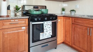 Een keuken met houten kastjes, een roestvrijstalen fornuis en een granieten aanrecht.